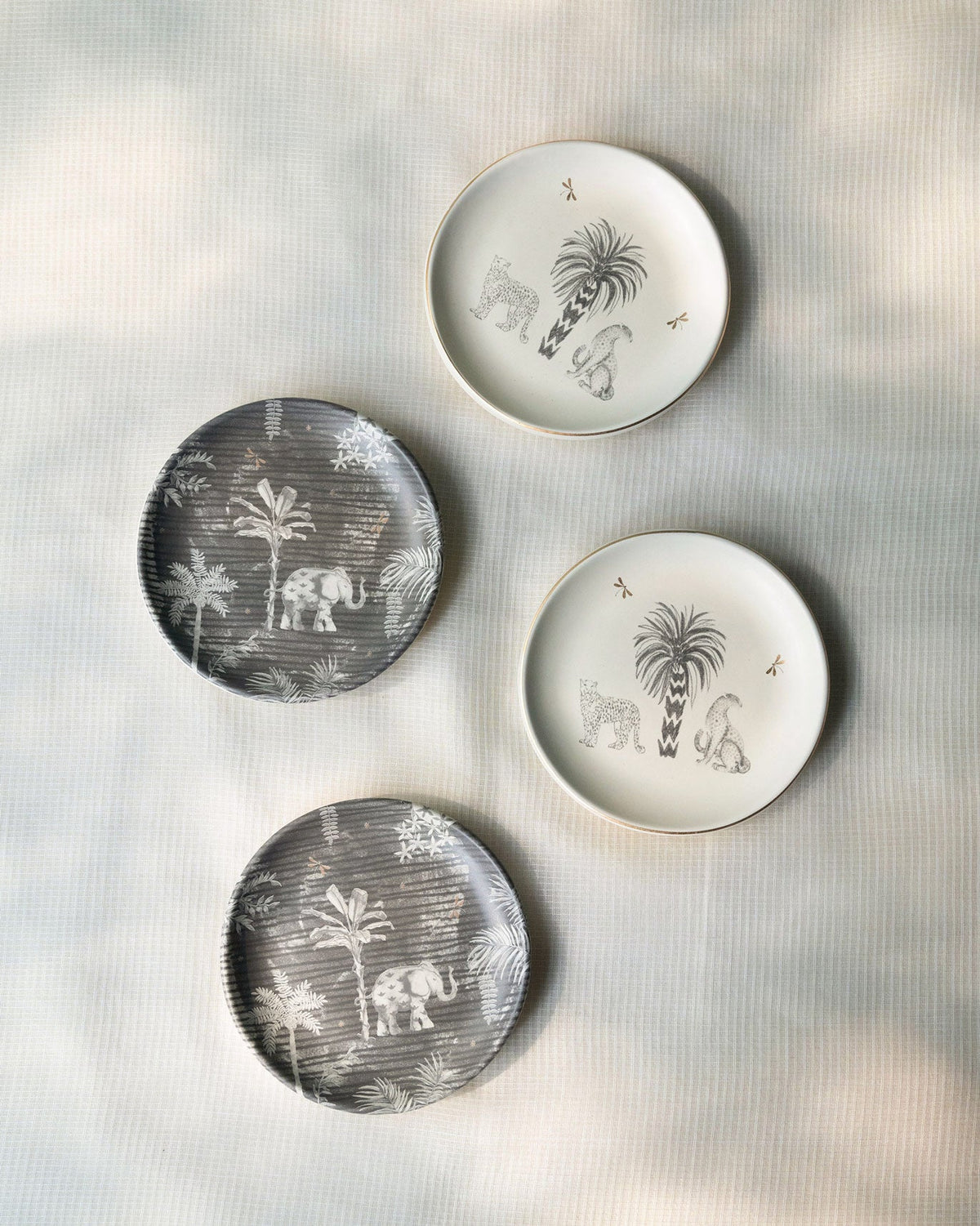 Periyar Tea Plates set of four, two grey and two white with palm and animal designs.