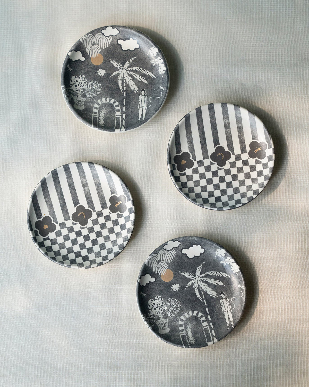 Four Mandovi Tea Plates in grey with palm, cloud and check designs.