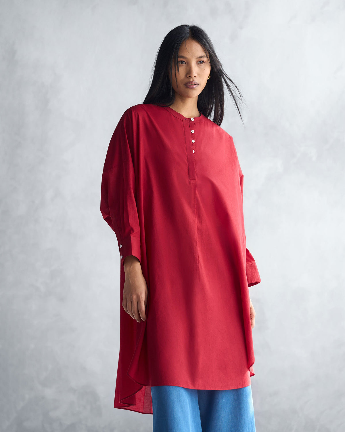 Person wearing a red Lazy Sunday tunic with a mandarin collar and buttoned placket.