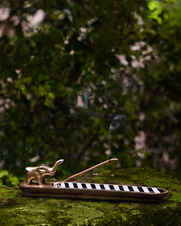 Brass Haathi incense holder with a striped tray and lit incense.