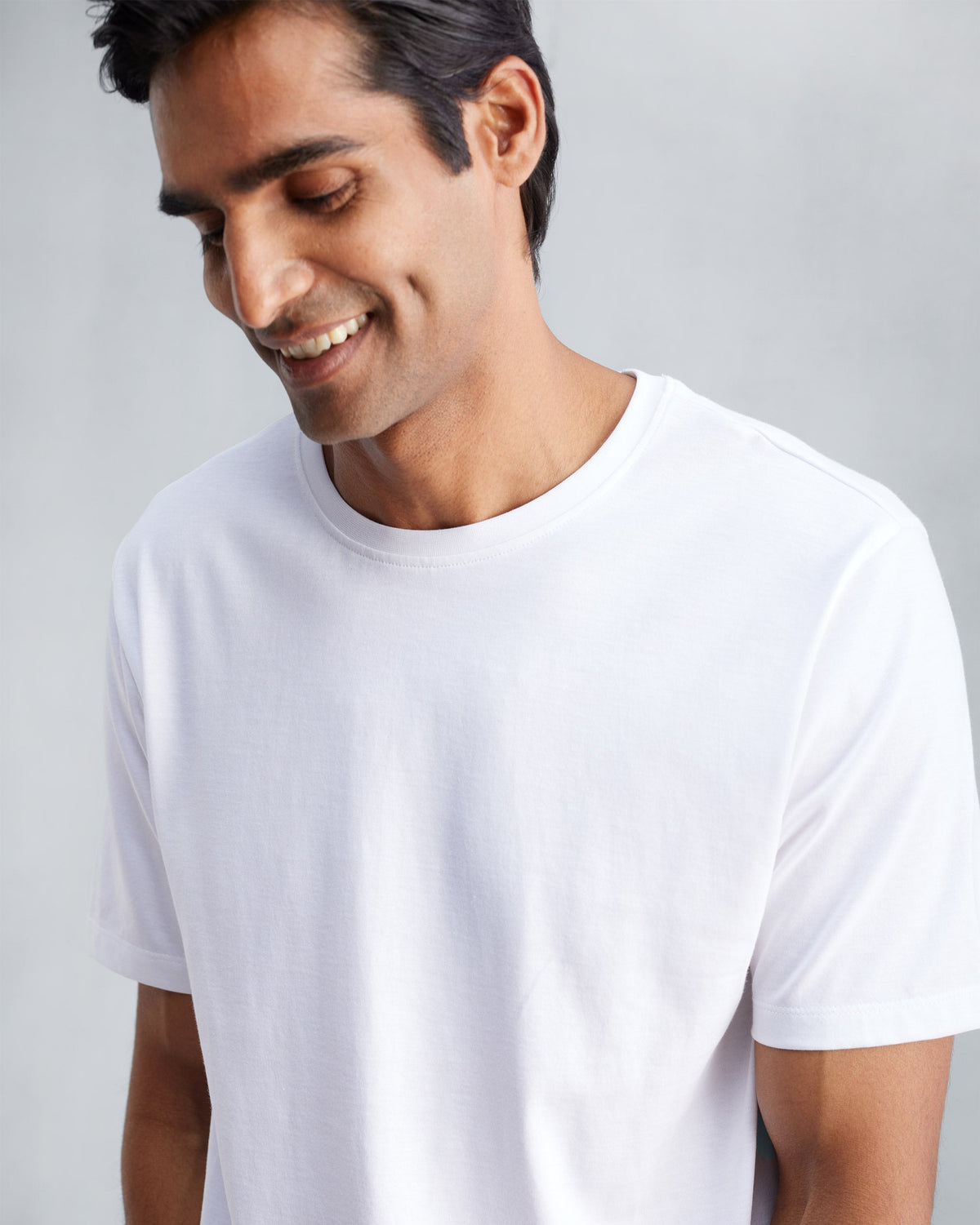 Person wearing a white Everyday T-shirt with a ribbed crew neck.
