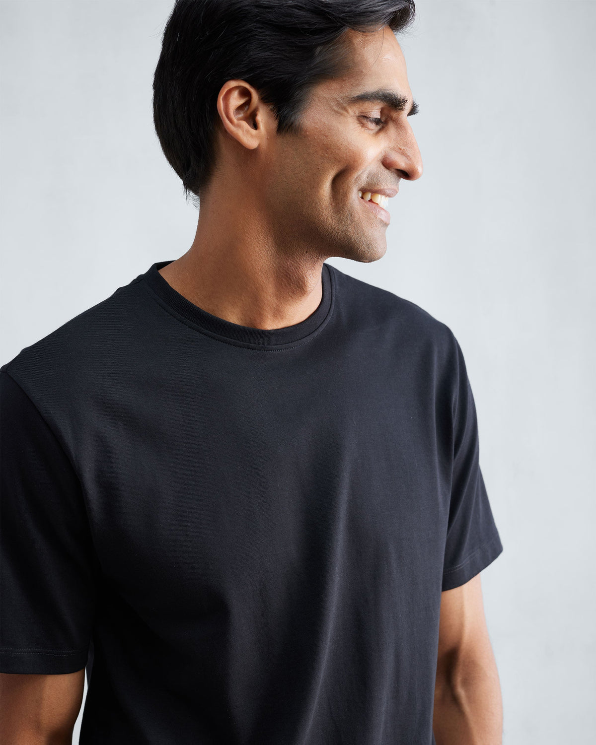 Person wearing a black Everyday T-shirt with a ribbed crew neck.