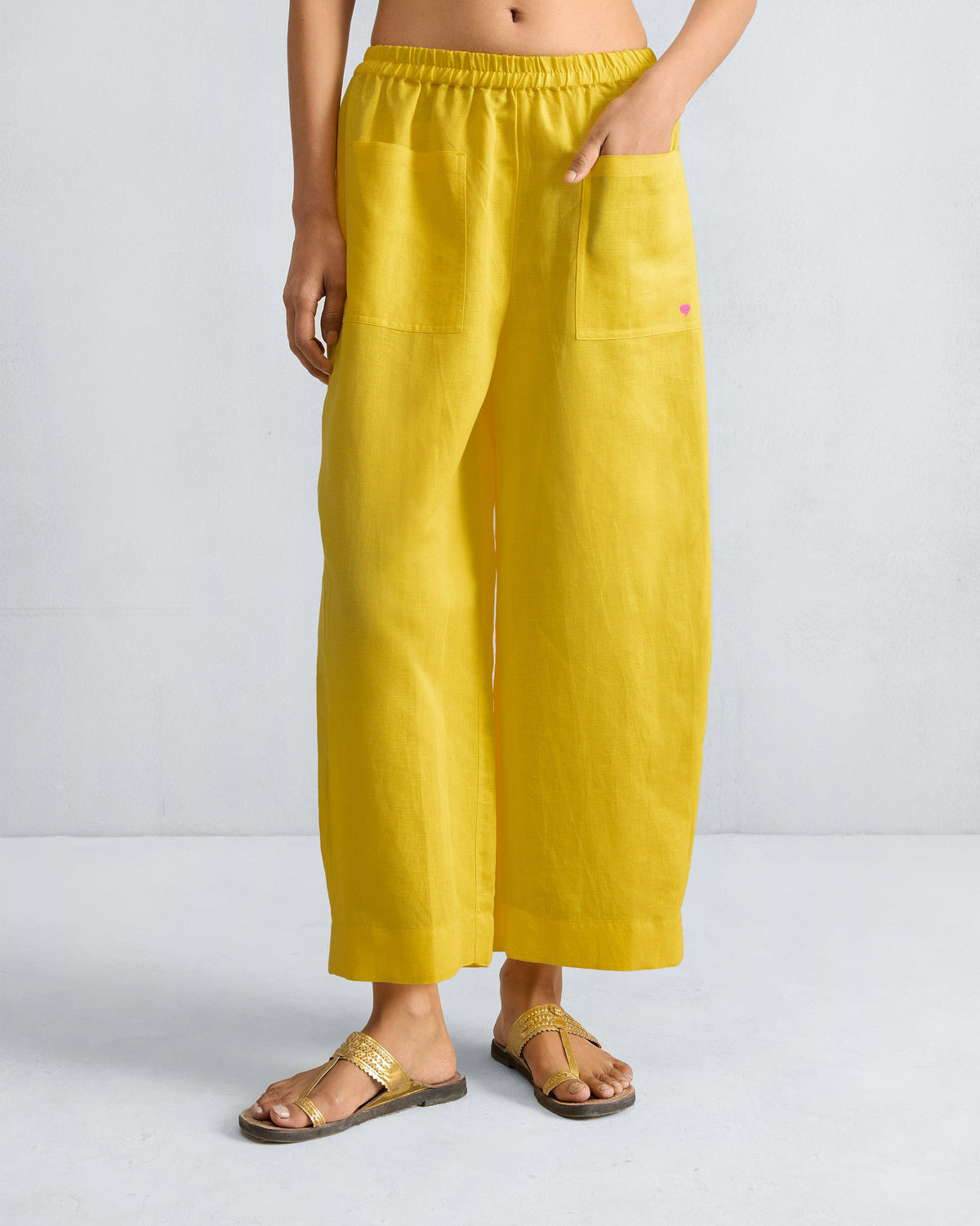 Person wearing yellow Serene pants with front patch pockets and a pink heart.