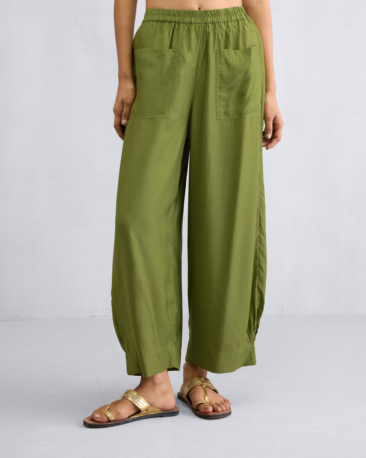 Person wearing olive Serene pants with front patch pockets and wide legs.