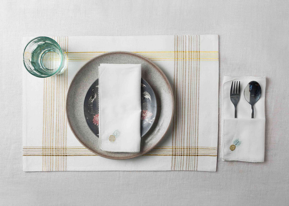 Chin-Chin Pineapple Napkin on a table setting with cutlery tucked in a pocket.