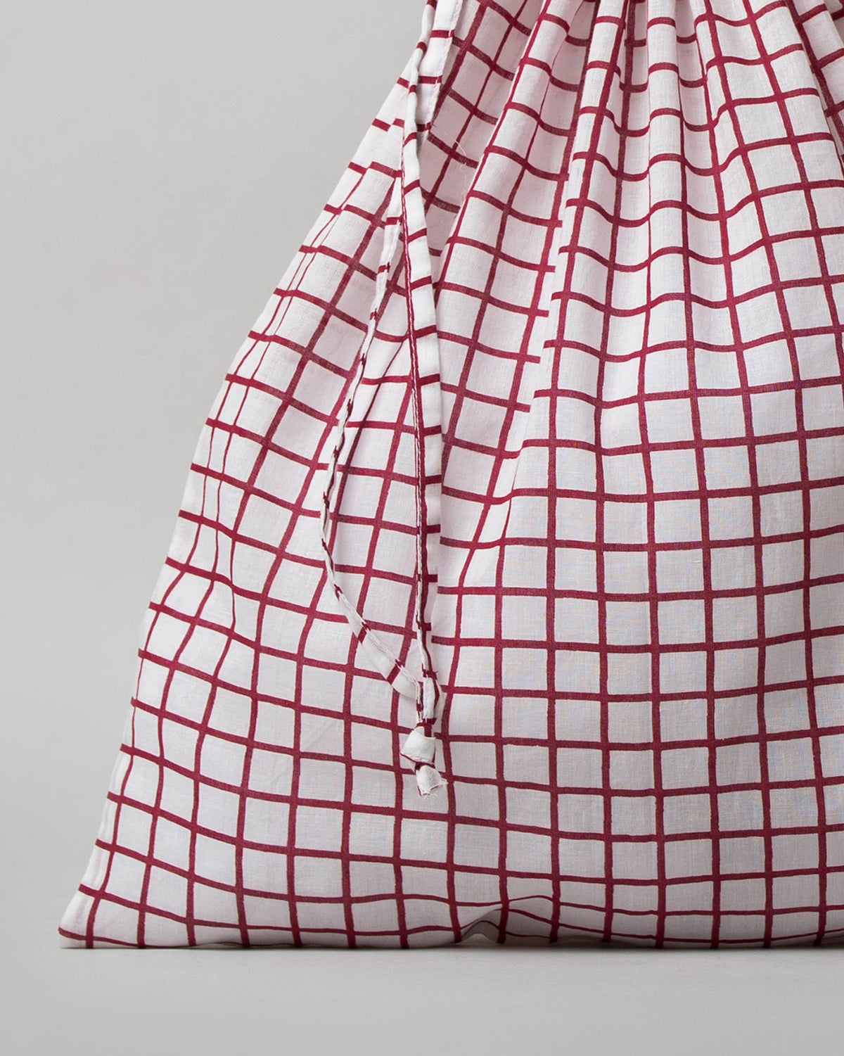 Close-up of a Check Wear Bag showing its red grid check and drawstrings.