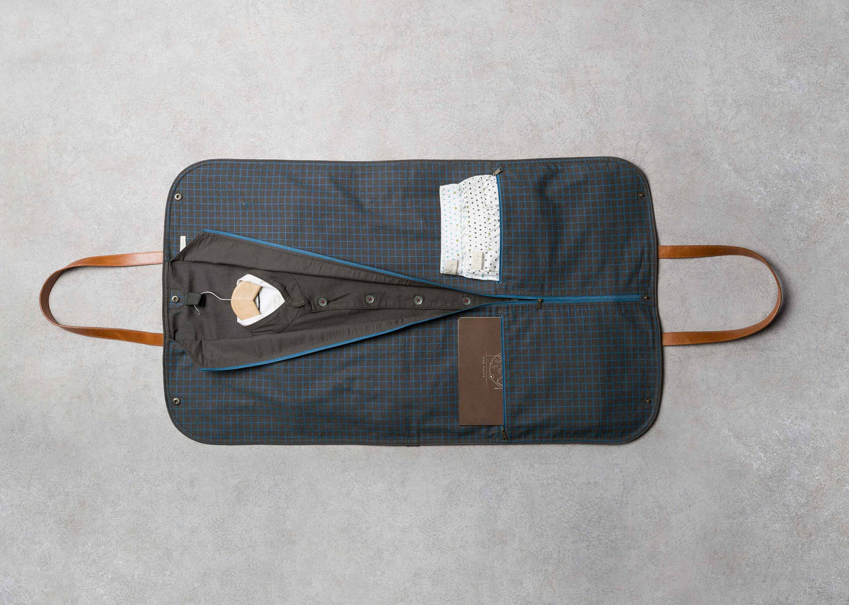 Hanging Coat Bag laid open flat, showing its navy check interior and tan handles.