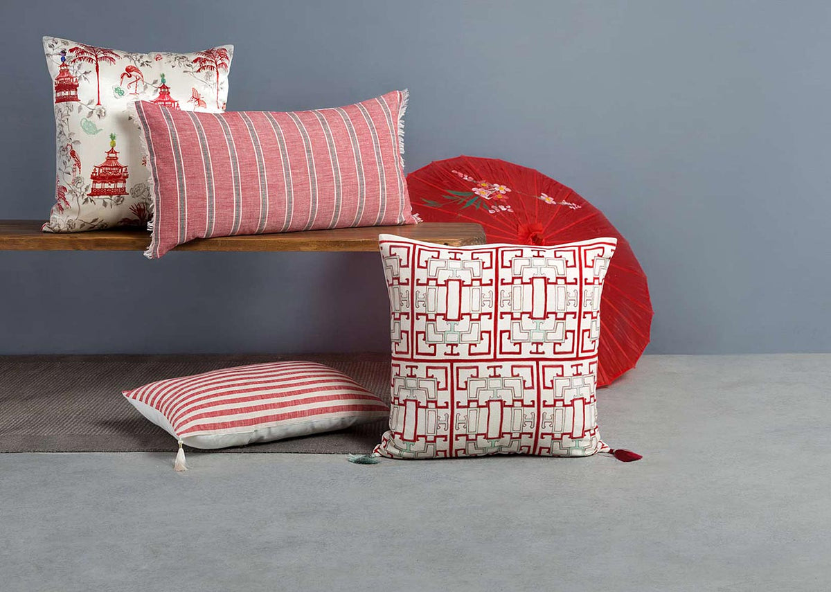 Chi Cushion Cover in red and cream placed on a grey floor.