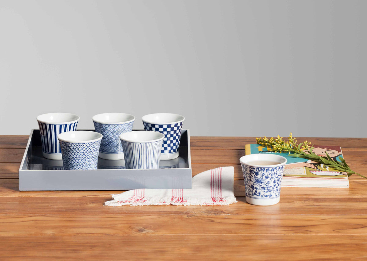 Sencha tea cups in blue and white patterns on a grey tray beside a book.
