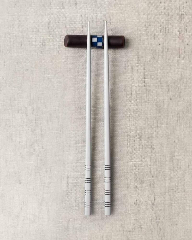 Checkered Chopstick Rest with a pair of grey chopsticks resting on it.