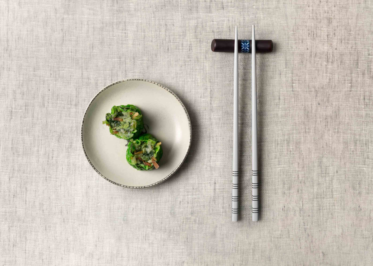 Aiiro Chopstick Rest with chopsticks in place, shown on a table beside a plate.