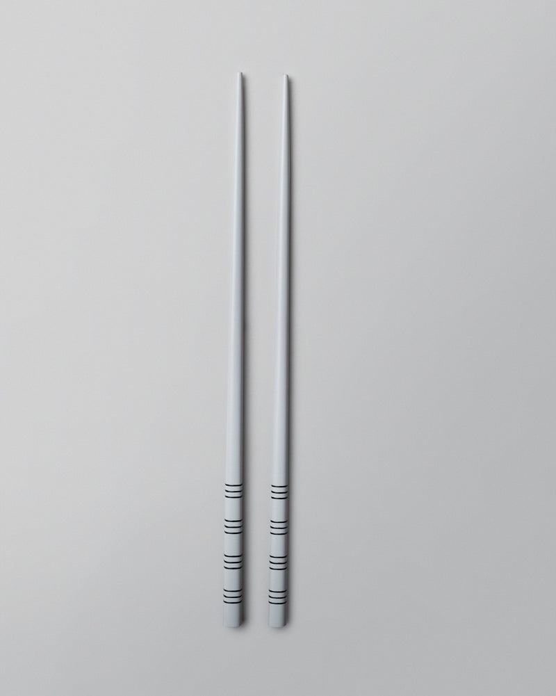 Pair of Stripe White Chopsticks laid flat on a grey surface.