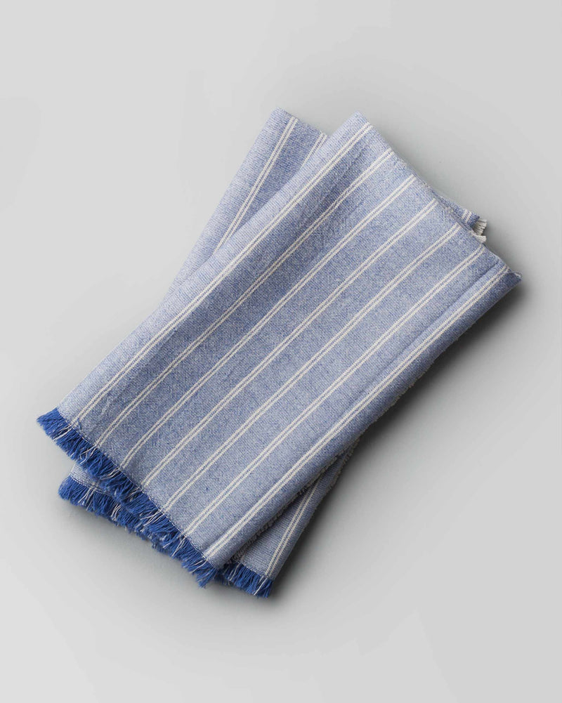 Daburu Stripe Dinner Napkins in blue with white stripes and fringed edges.