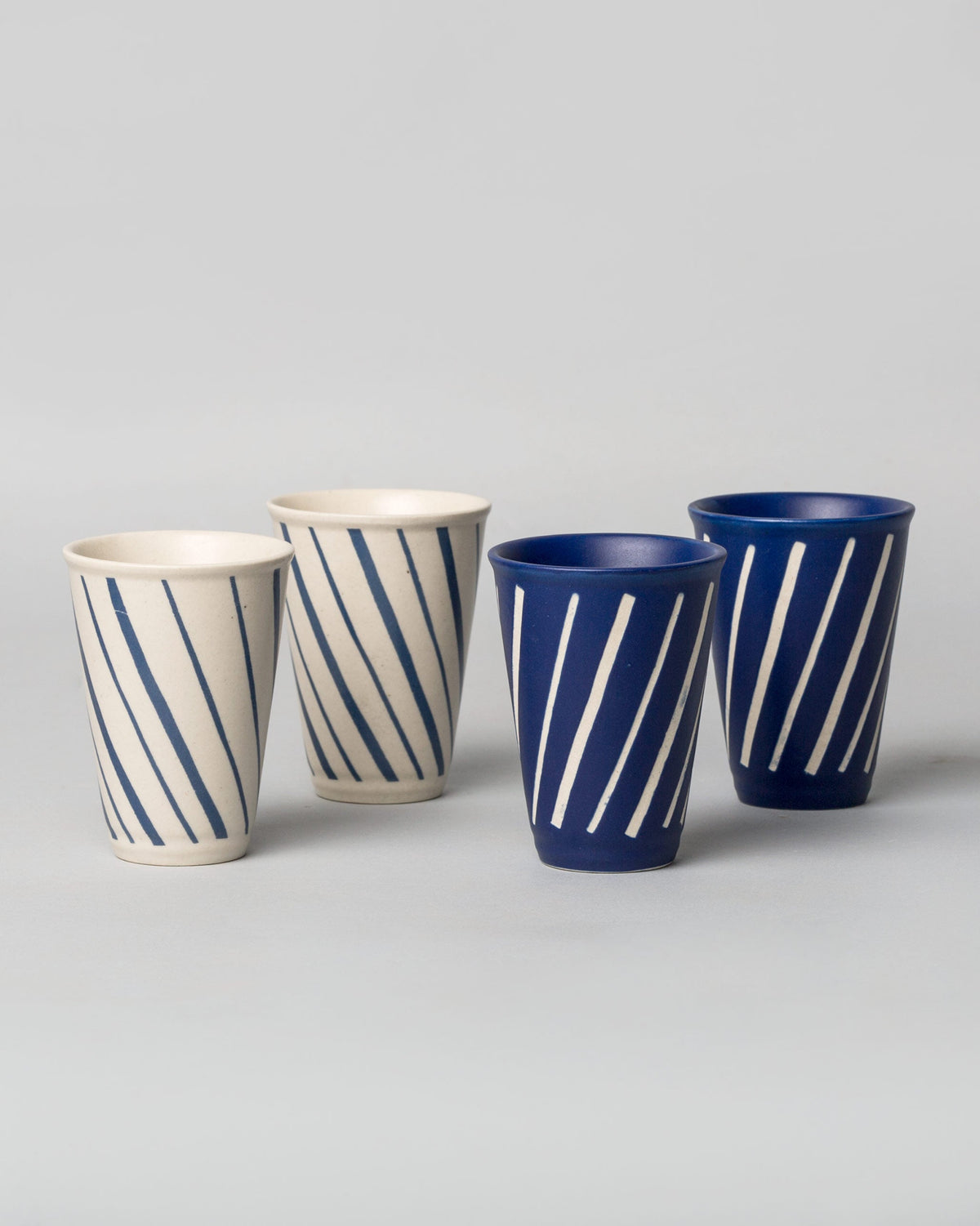 Four Aozora Kulhar cups in cream and dark blue with striped designs.