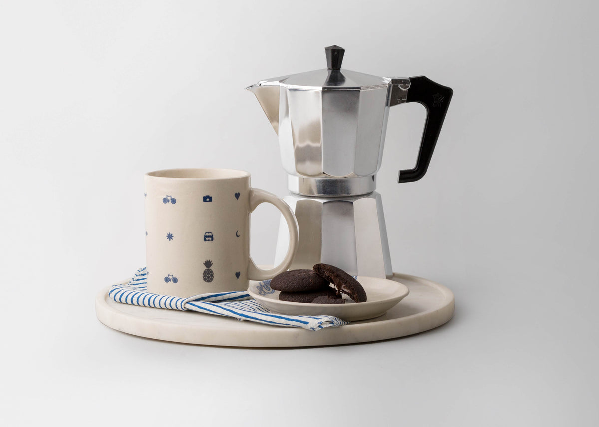 Icon Mug with blue icons on a round tray in a styled setting.