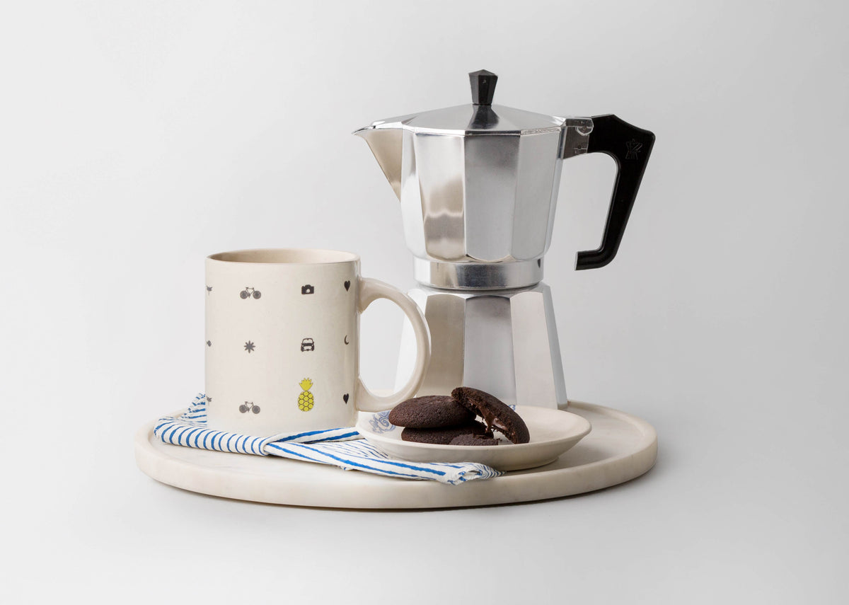 Icon Mug with charcoal icons on a round tray in a styled setting.