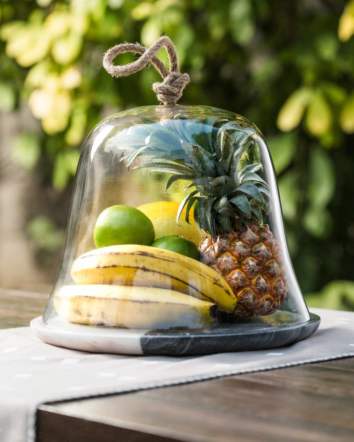 Ceylon cheese dome in use, covering fruit on a grey and white base.
