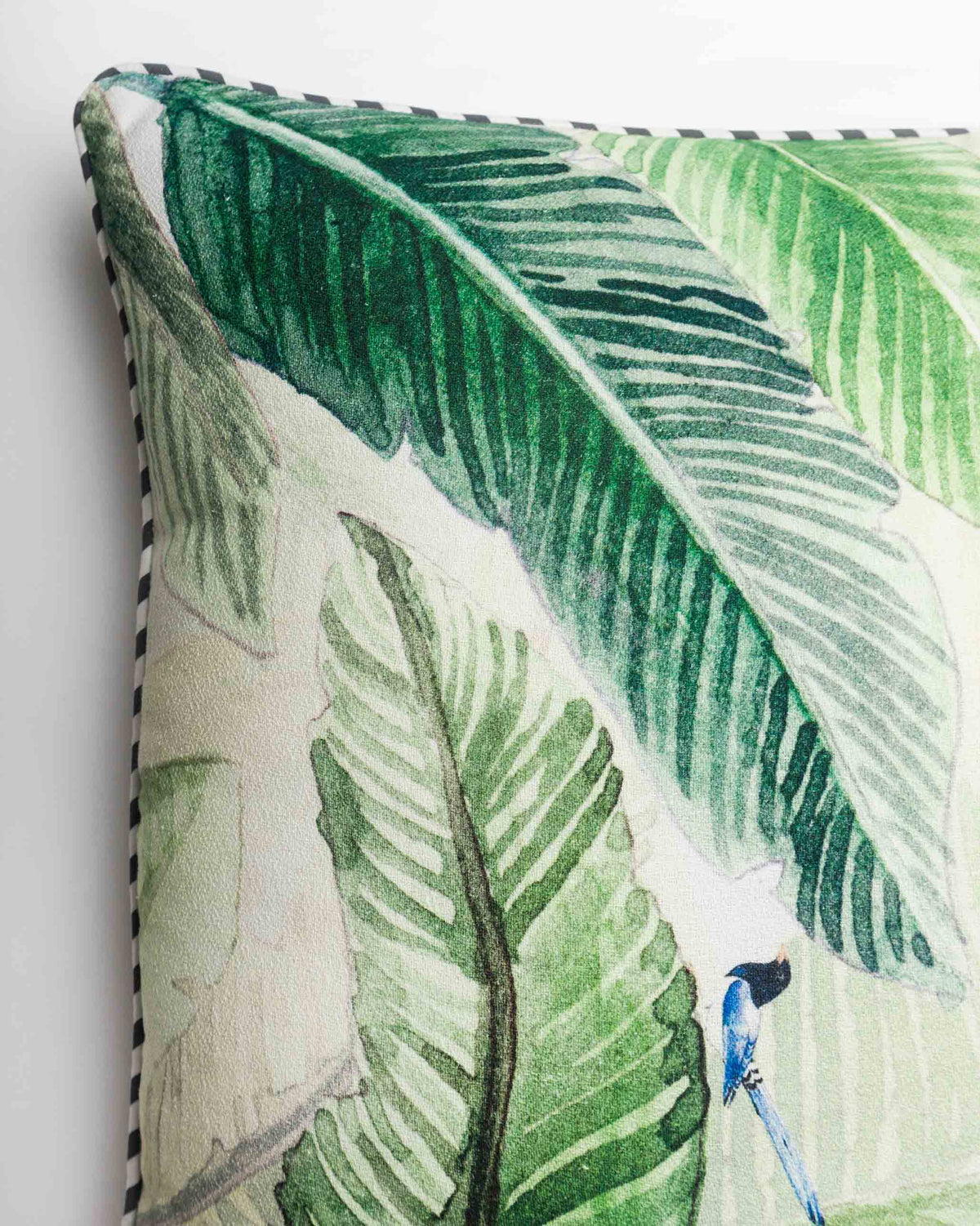 Close-up of the Banana Leaf Cushion Cover showing a blue bird among the leaves.