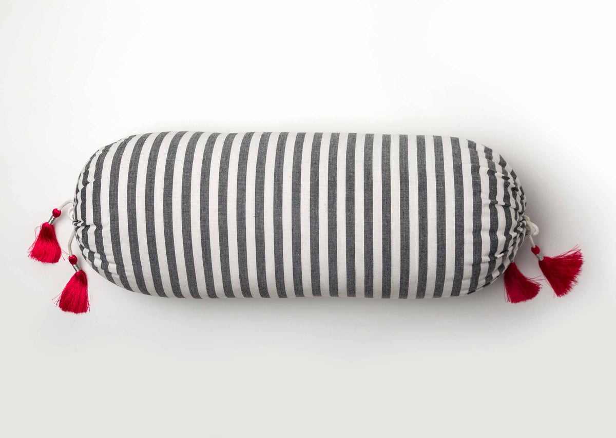 Black and white striped bolster cover with pink tassels at both ends.