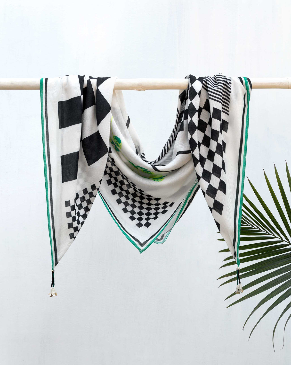 Lunuganga Scarf hung over a rail, with black and white checks and green edging.