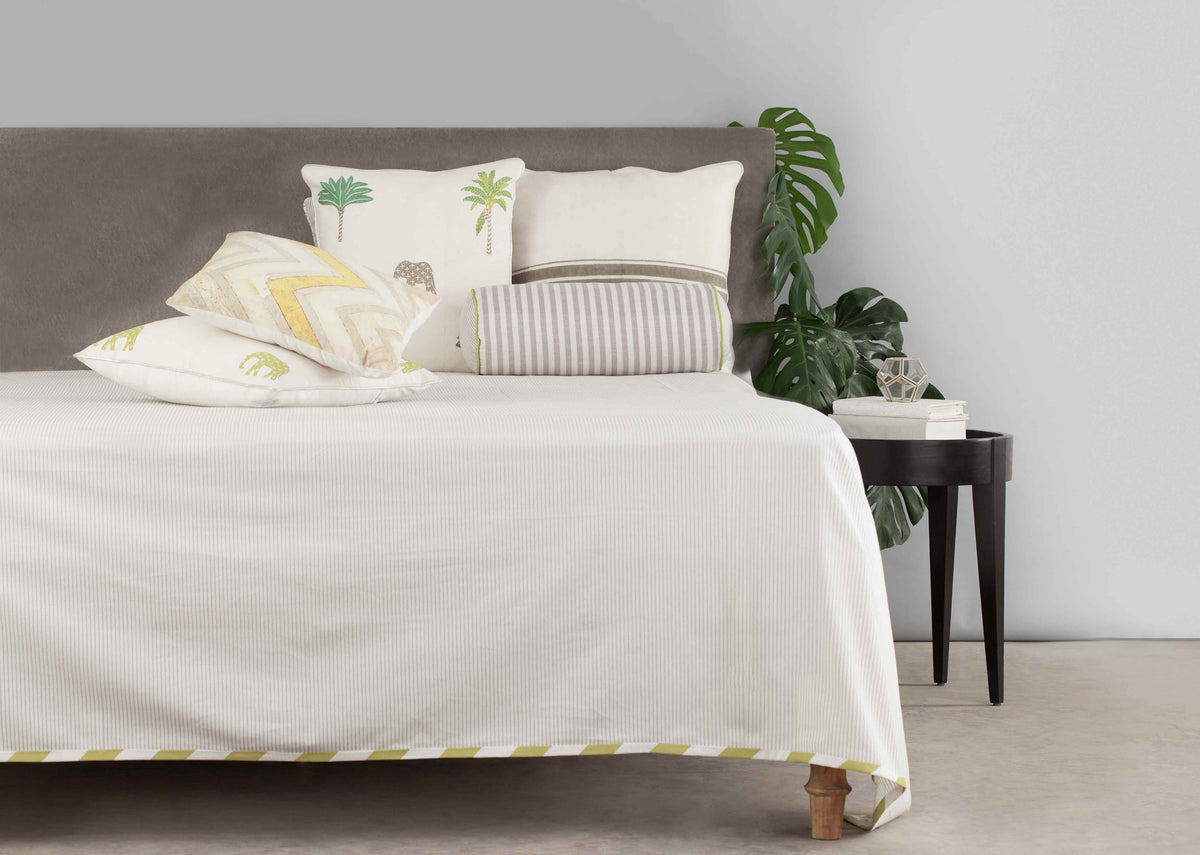 Alleppey Stripes Bolster Cover styled on a bed with other cushions.