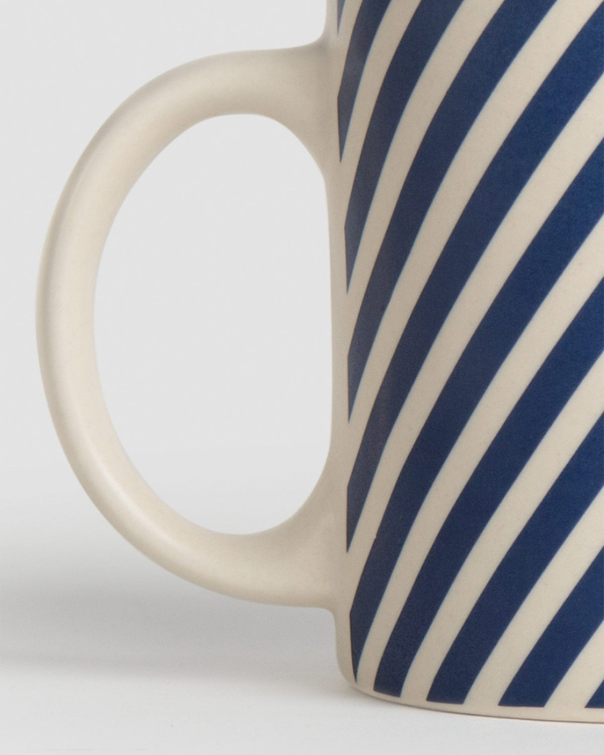Close-up of the Kumarakom candy stripe mug showing its cream handle and blue stripes.