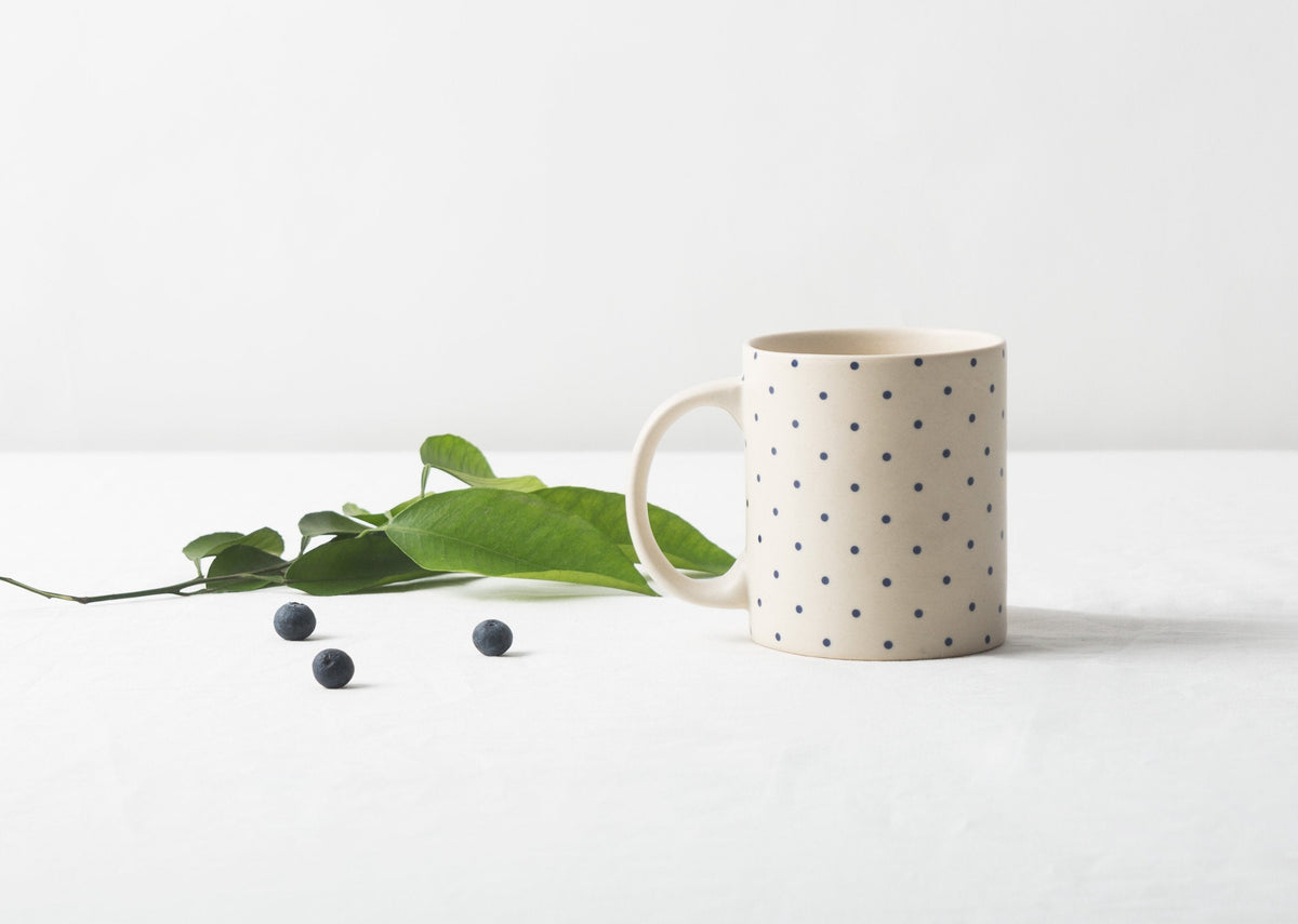 Kumarakom polka dot mug with navy dots on a white table.