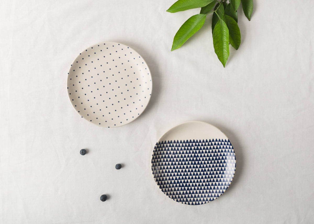 Kumarakom Cloudburst quarter plates on linen, one with blue triangles and one with dots.