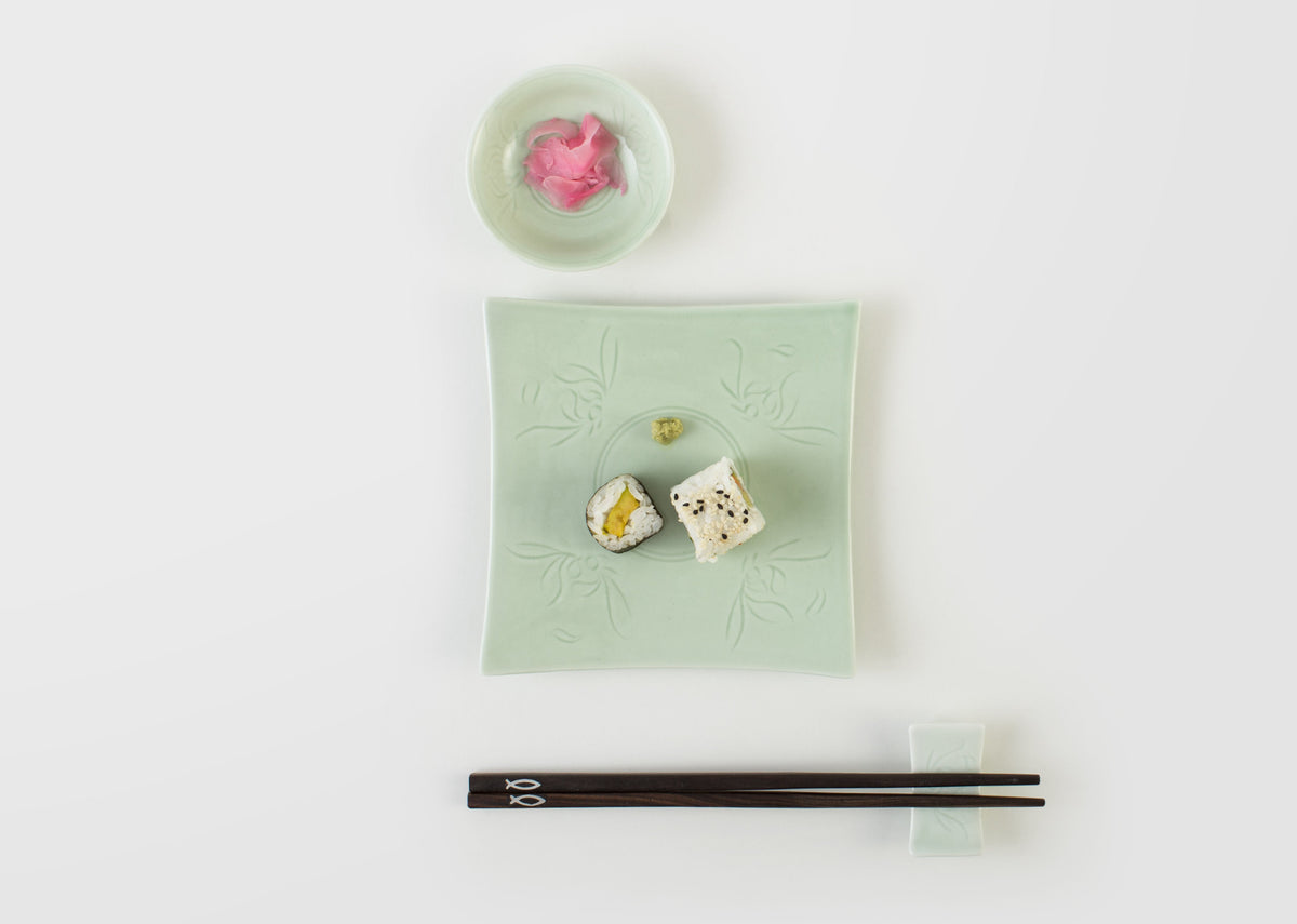 Celadon Square Plate holding two sushi rolls, with a small dish and chopsticks nearby.