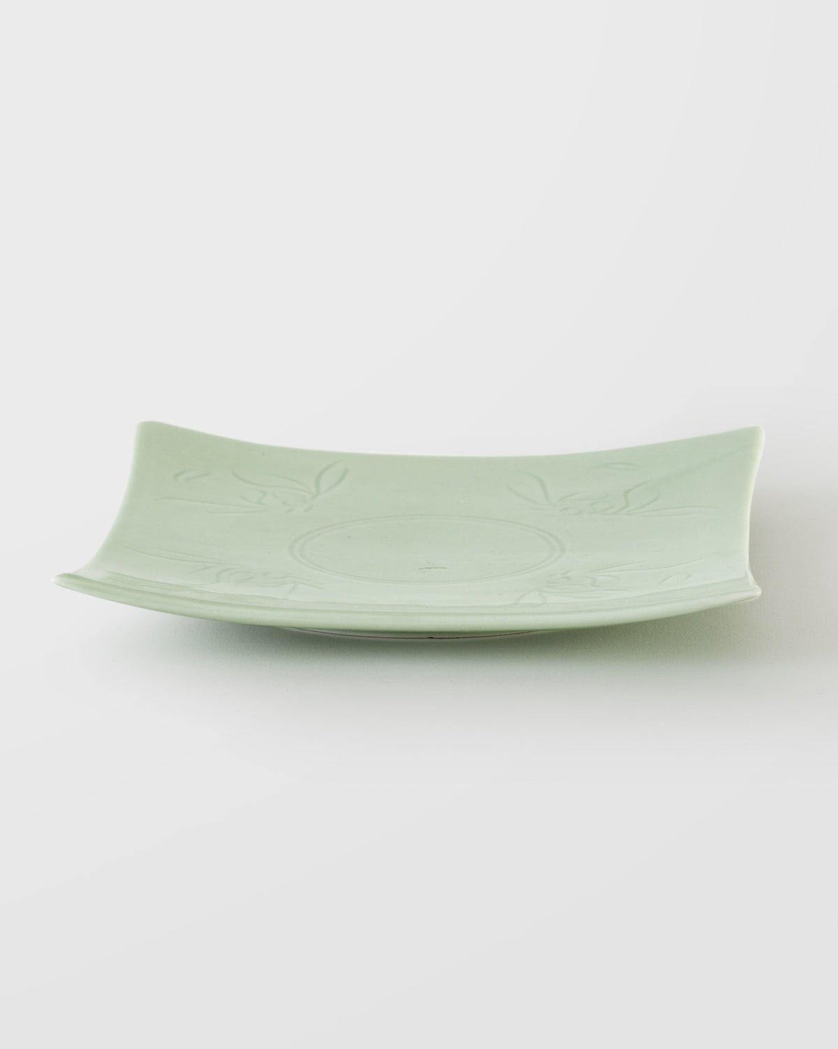 Side view of a Celadon Square Plate with raised edges and leaf motifs.