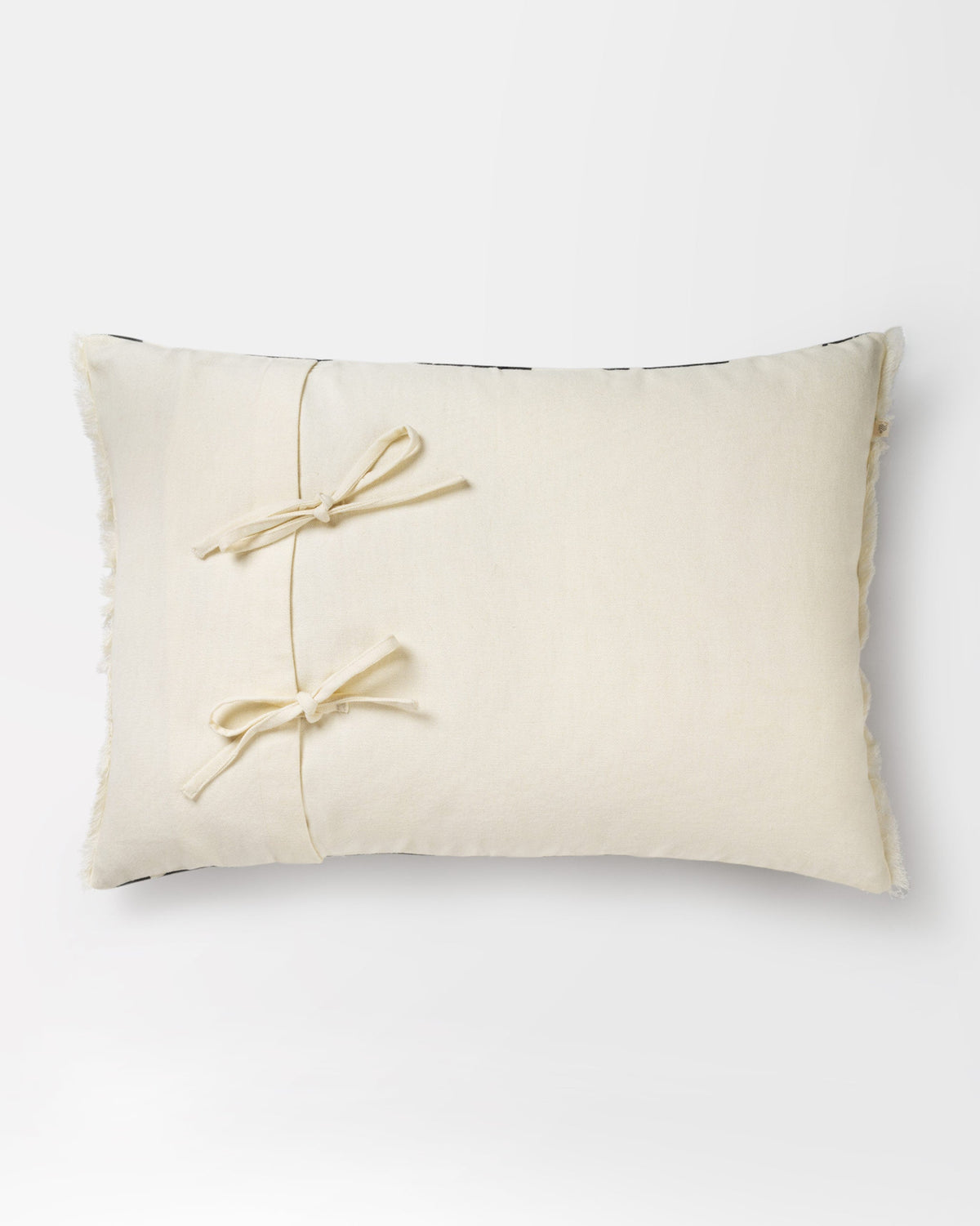 Back of a Giza Pillow Cover in plain cream with tie closures.