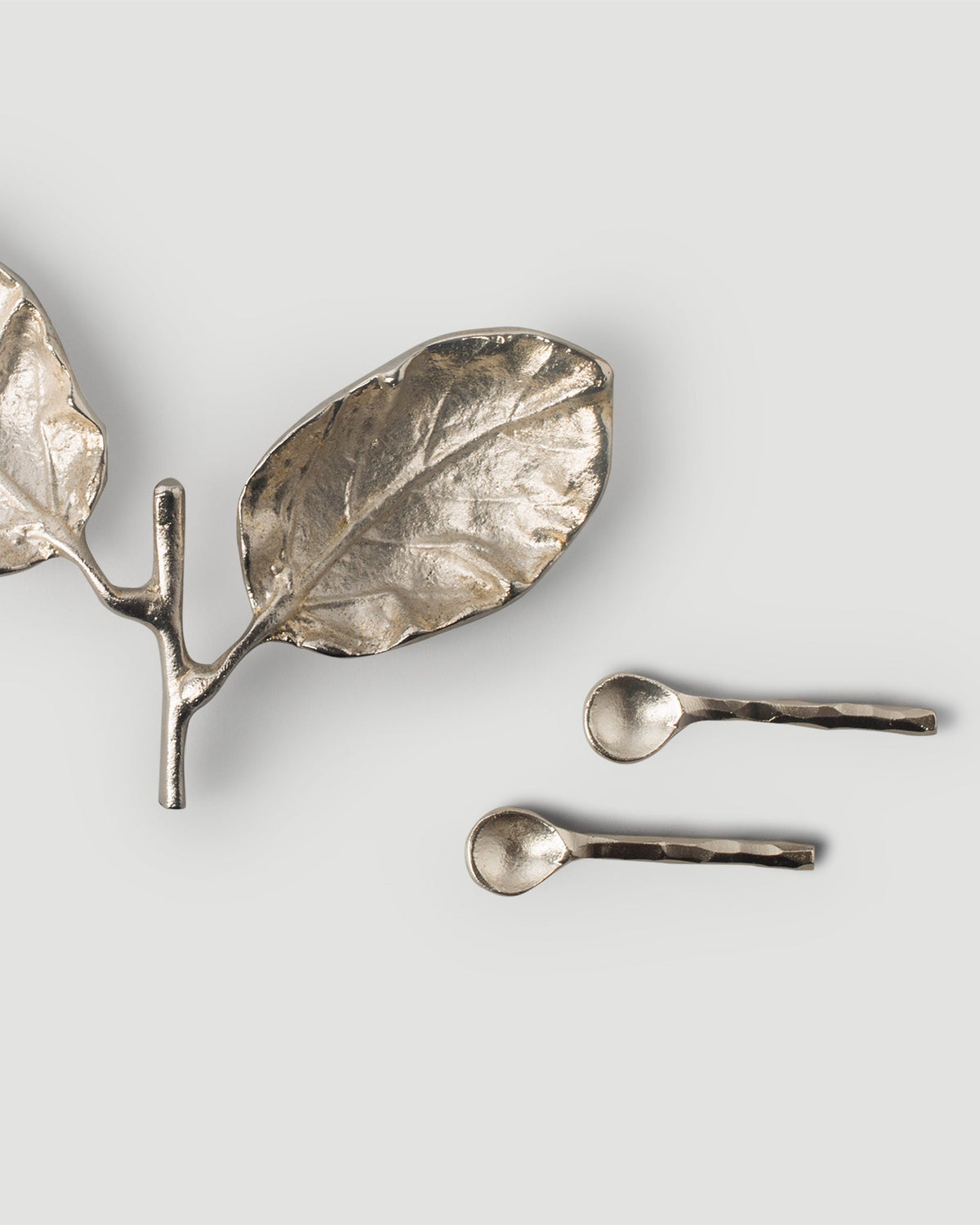 Close-up of a Leaf Pinch Pot leaf dish beside two small spoons.
