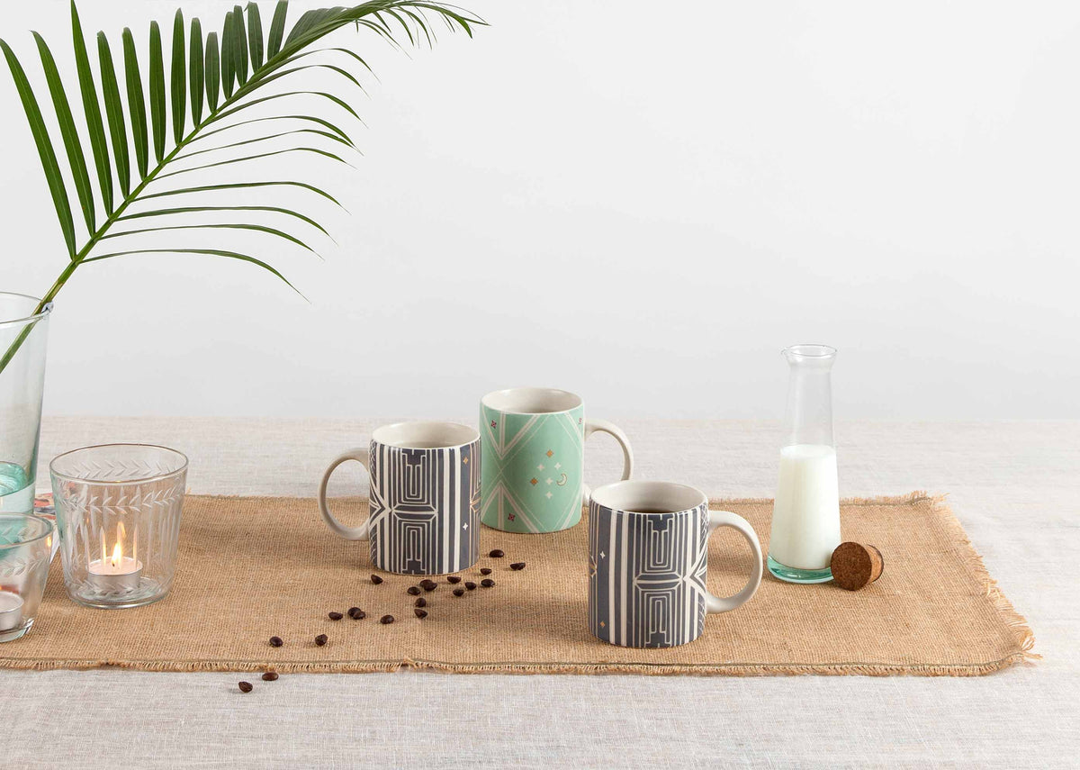 Chand Mug in mint among black and white patterned mugs on a table runner.