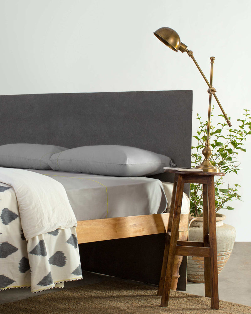 Solid Sheeting in grey with a lime edge line, dressed on a bed.