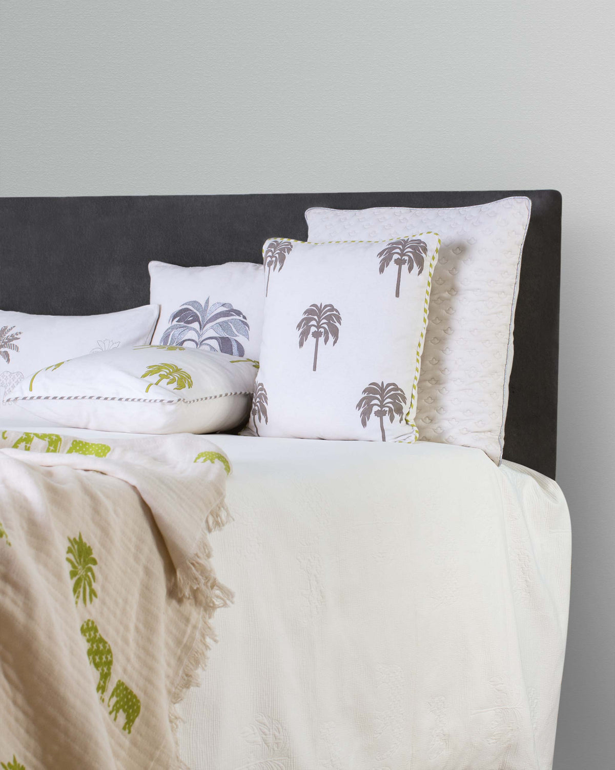 Colombo Palm Block Cushion Cover in soft grey, styled on a bed.