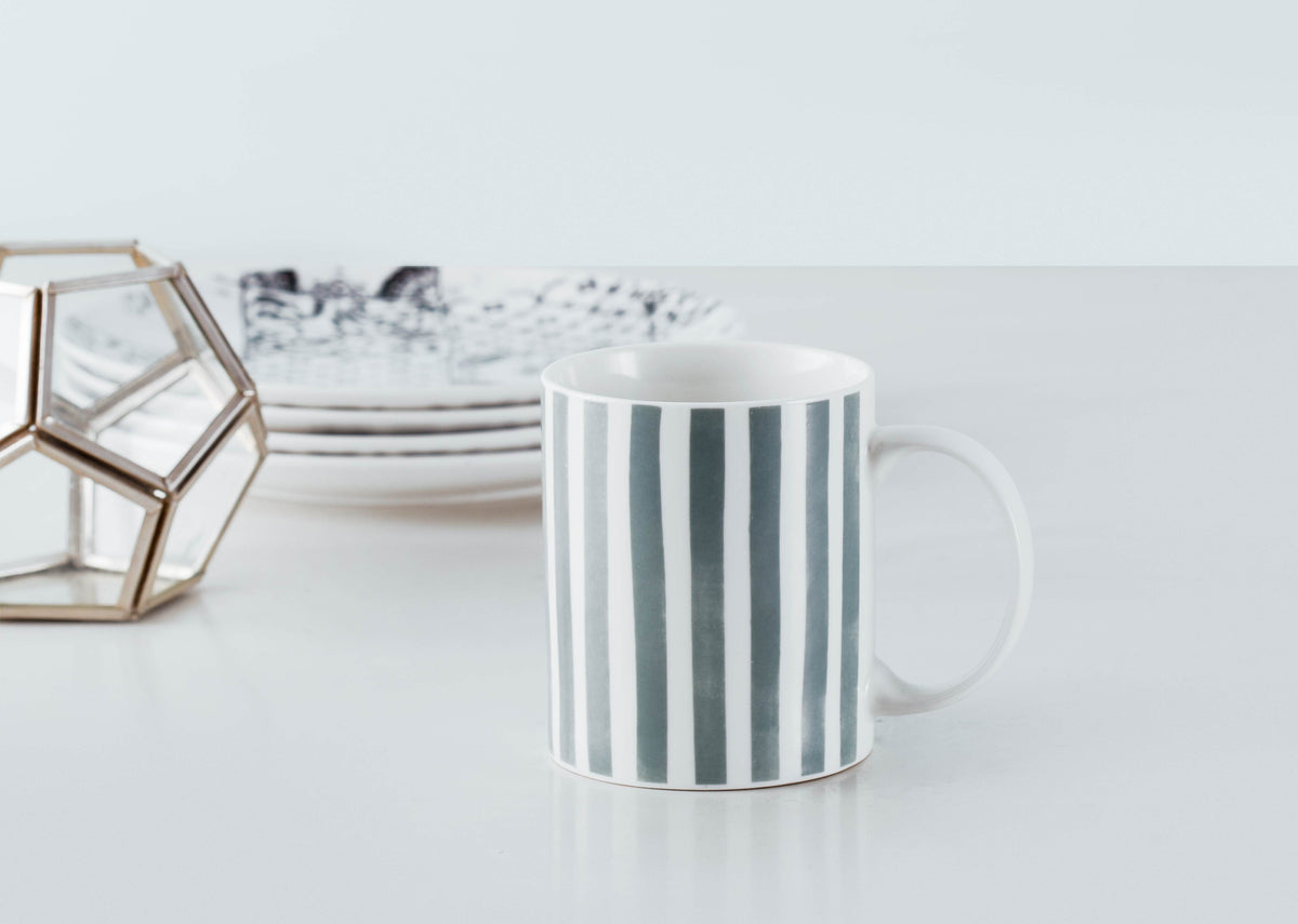 Flora Fauna Stripes Mug standing on a table.