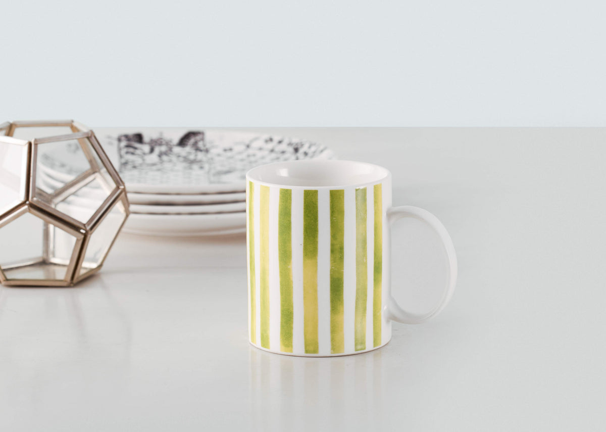 Flora Fauna Stripes Mug with lime green stripes, standing on a table.