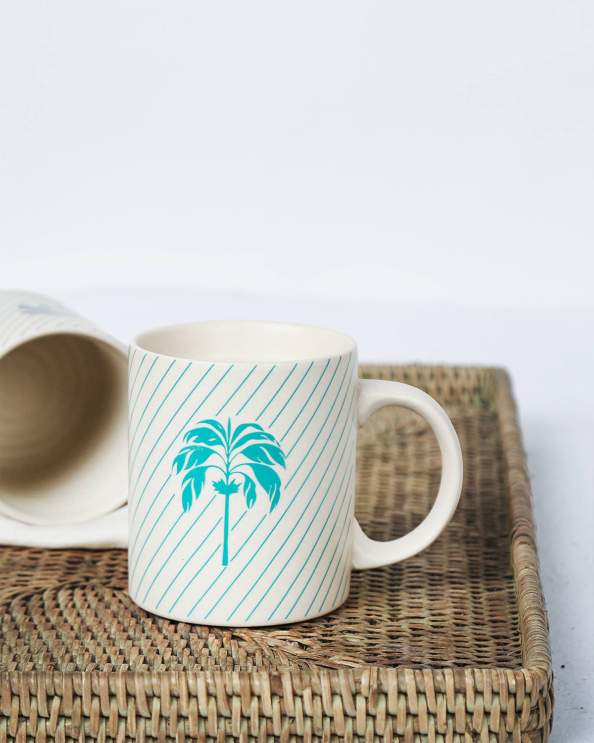 Palm Mug with an aqua palm tree, standing next to a second mug.