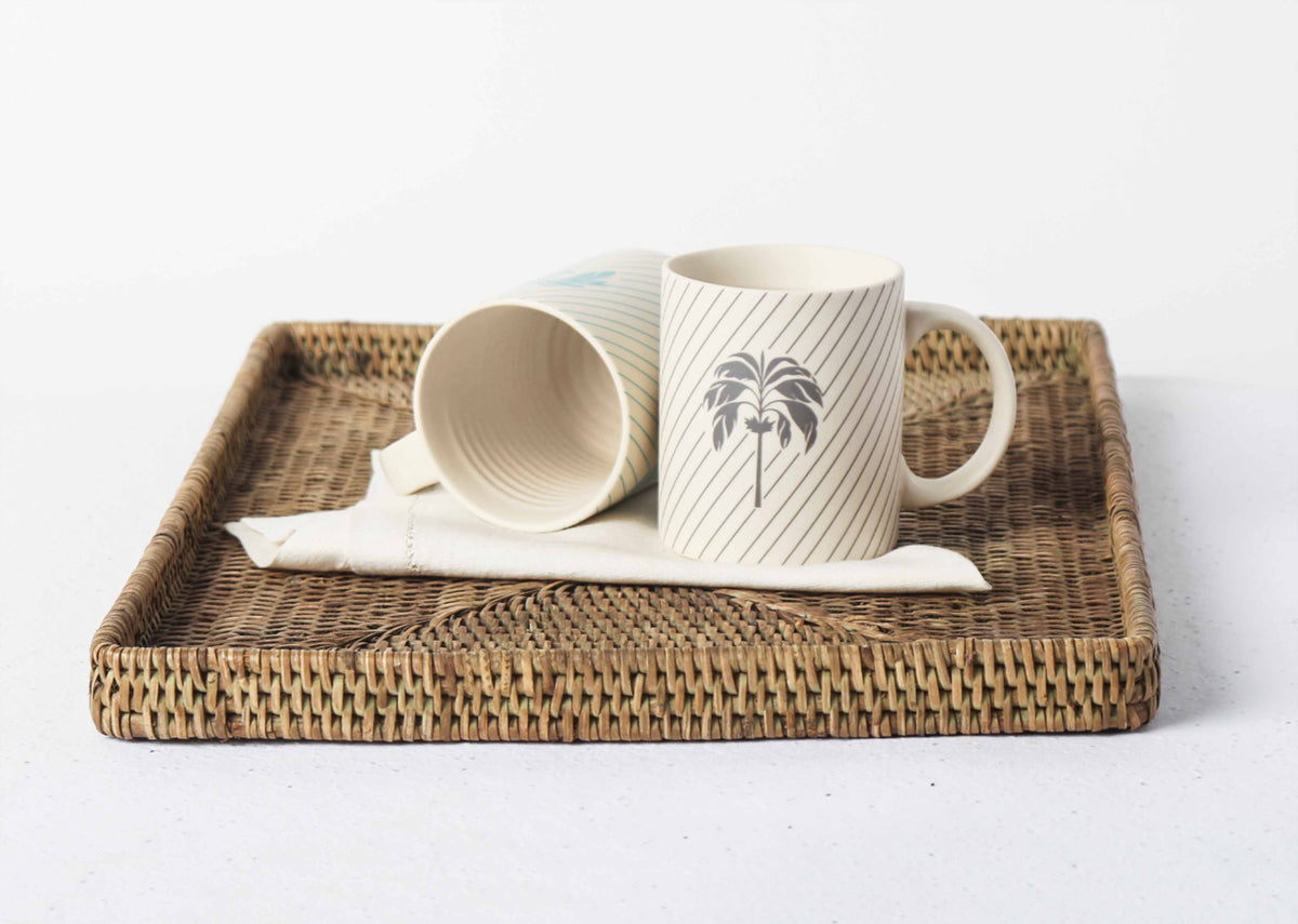 Palm Mug with a charcoal palm tree, standing beside a second mug.