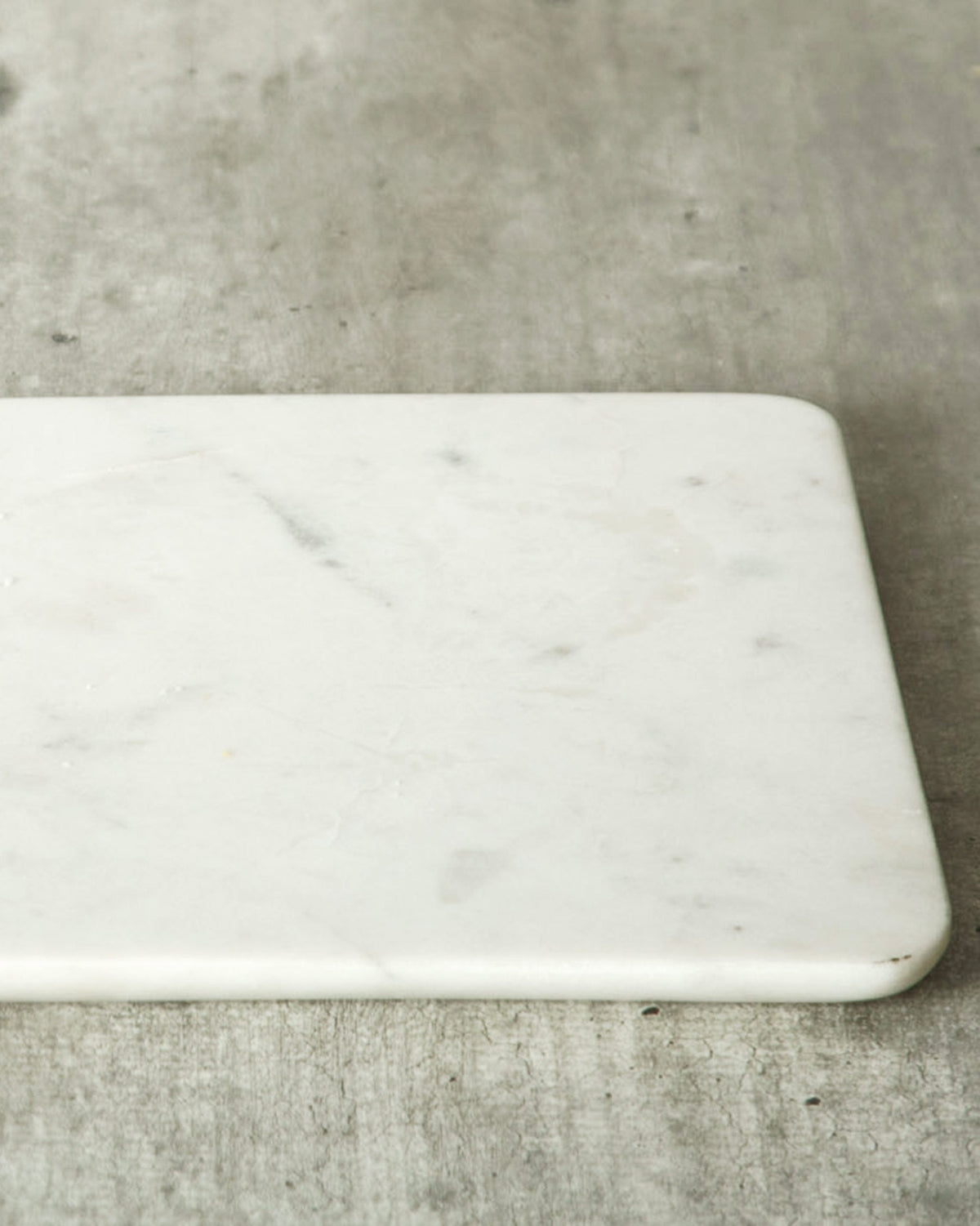 Side view of a Marble Cheese Board showing its thickness and rounded edge.