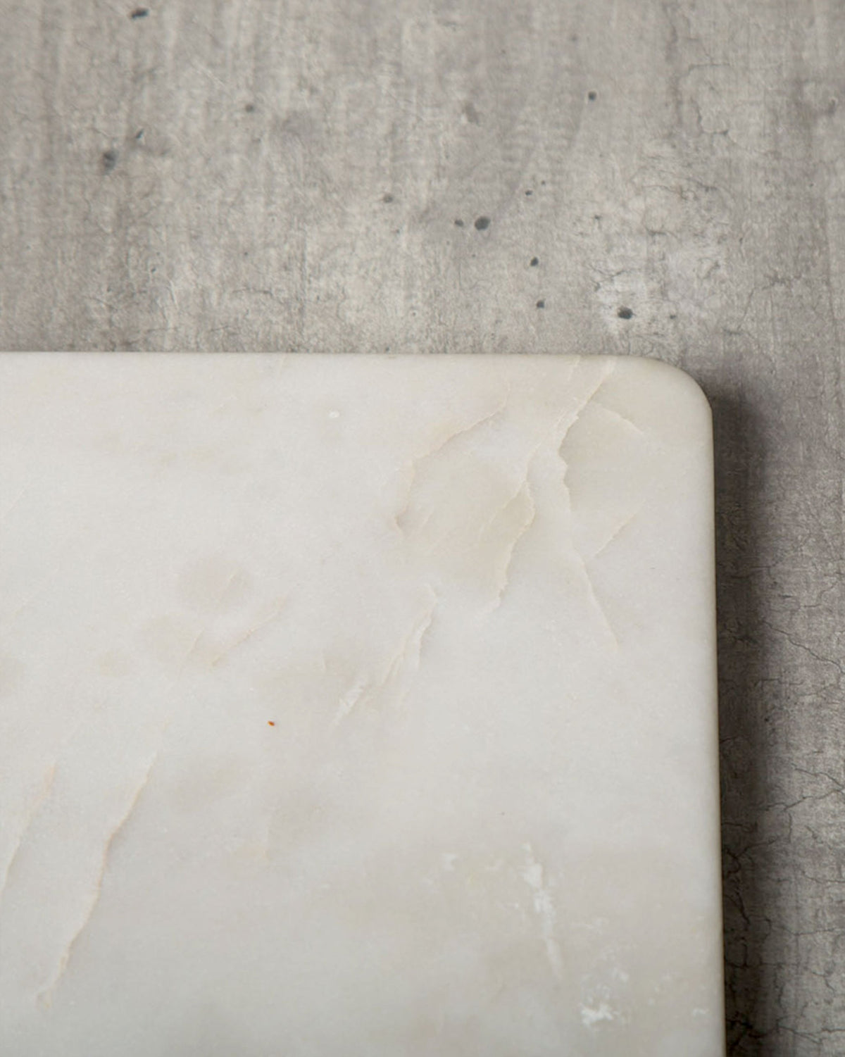 Close-up of a Marble Cheese Board corner showing its veining and rounded edge.