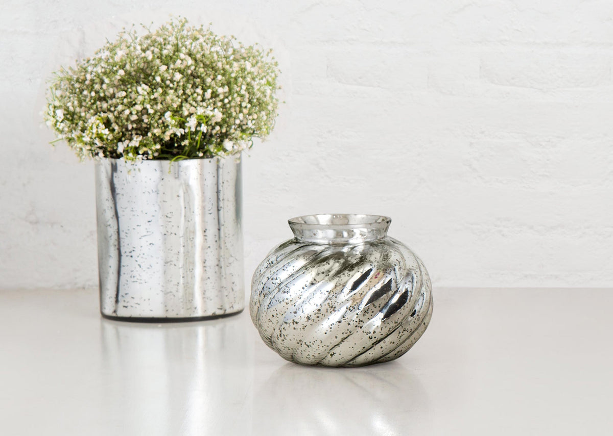 Andromeda Lota Vase in swirled speckled silver glass, beside a hurricane.