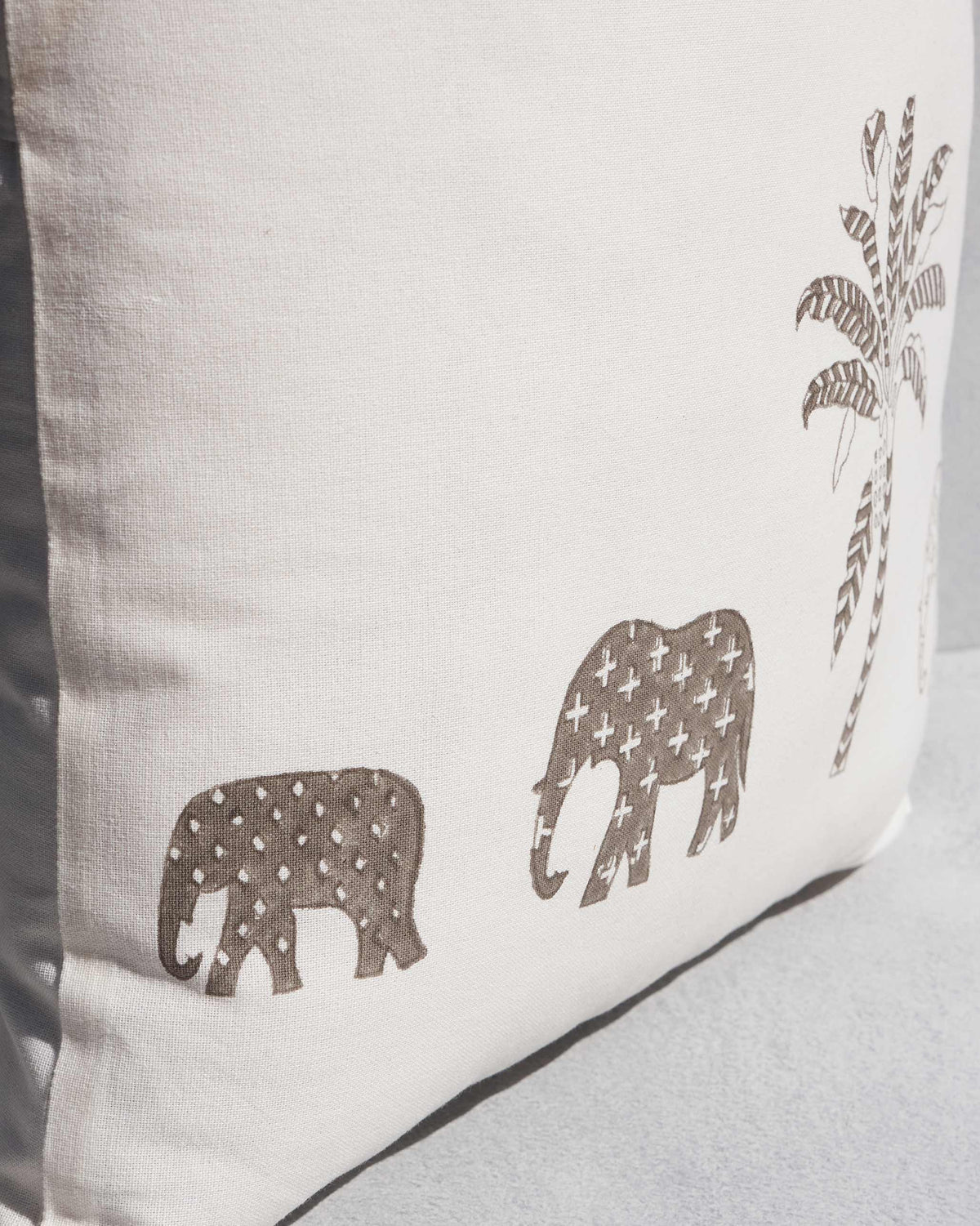 Close-up of Ele Palm Cushion Cover showing brown patterned elephants and a palm.