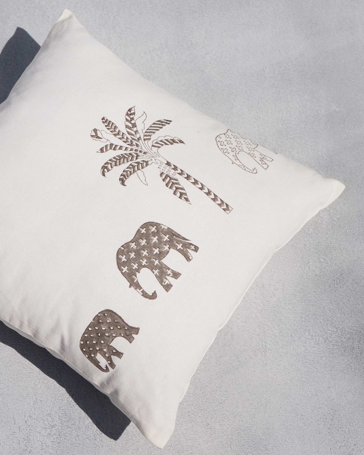 Angled view of Ele Palm Cushion Cover with a brown palm and elephants.