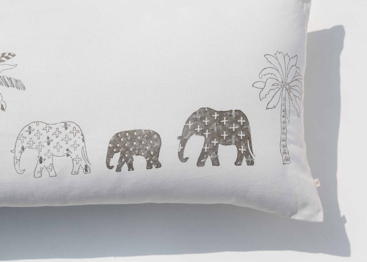 Close-up of Ele Palm Pillow Cover showing grey patterned elephants and a palm tree.