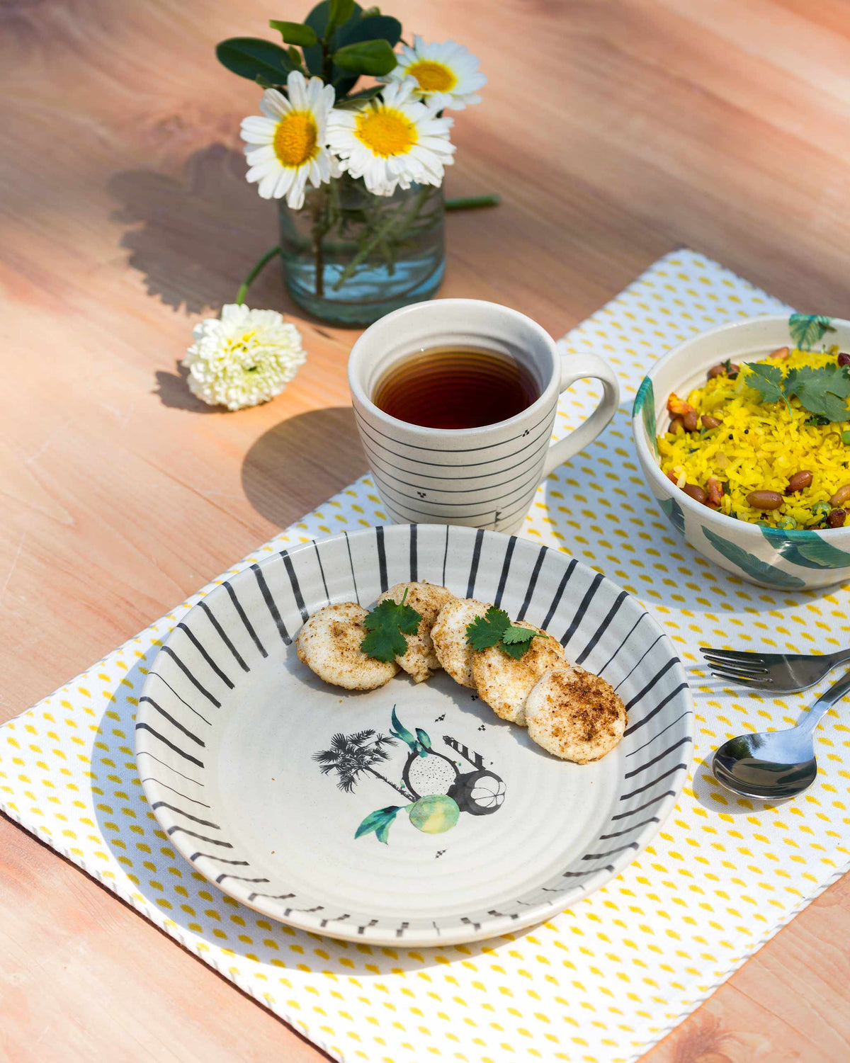Ceylon Breakfast Set plate holding small snacks, beside a mug of tea and a bowl of yellow rice.