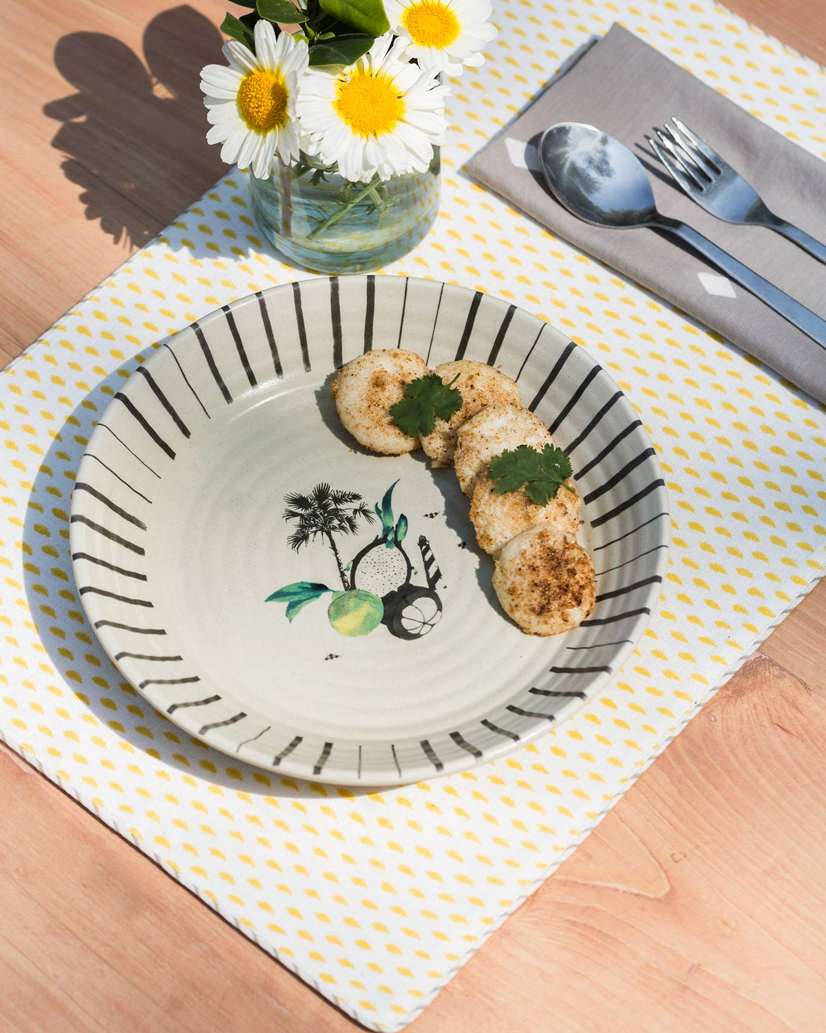 Ceylon Pasta Plate with a black striped rim, served with food on a placemat.