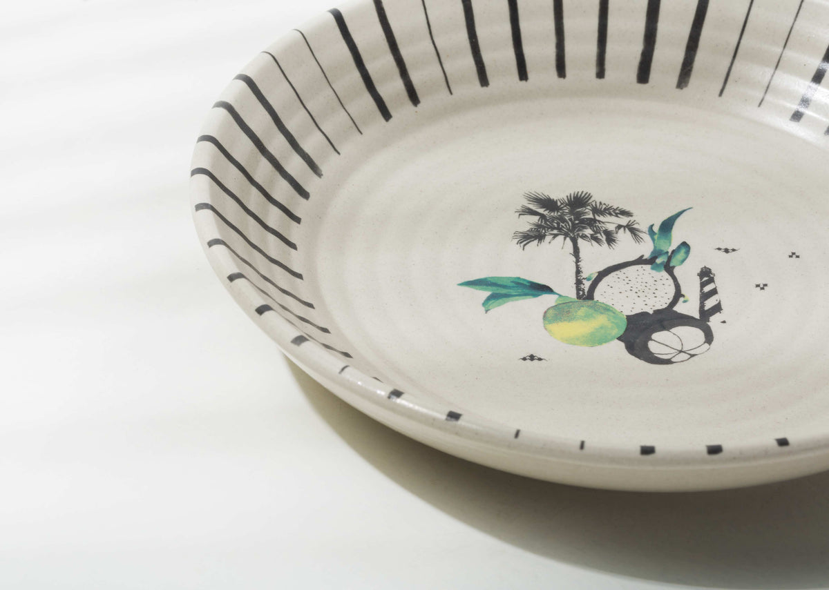 Close-up of the Ceylon Pasta Plate's striped rim and palm motif.