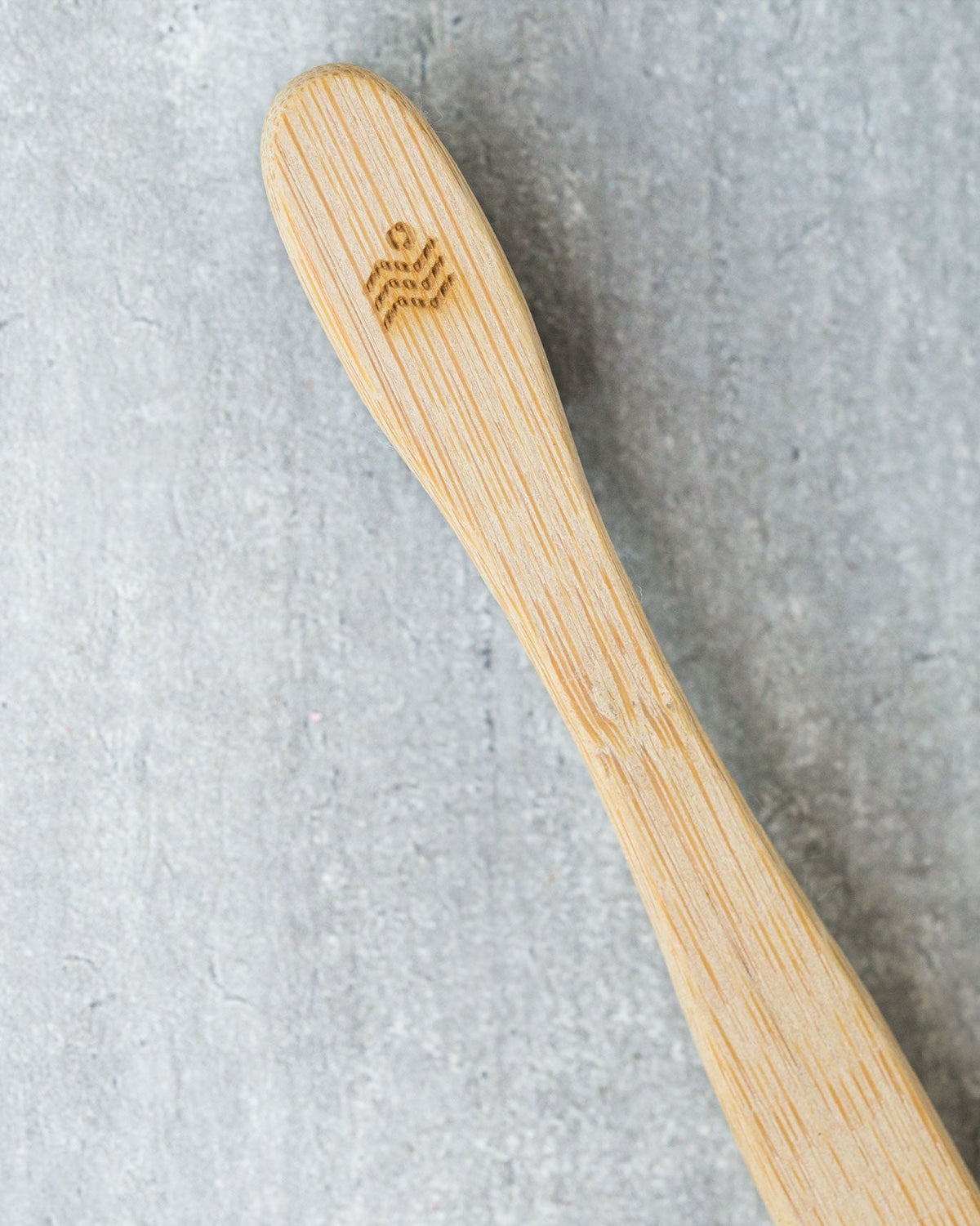 Close-up of a Bamboo Toothbrush handle with a small engraved logo.