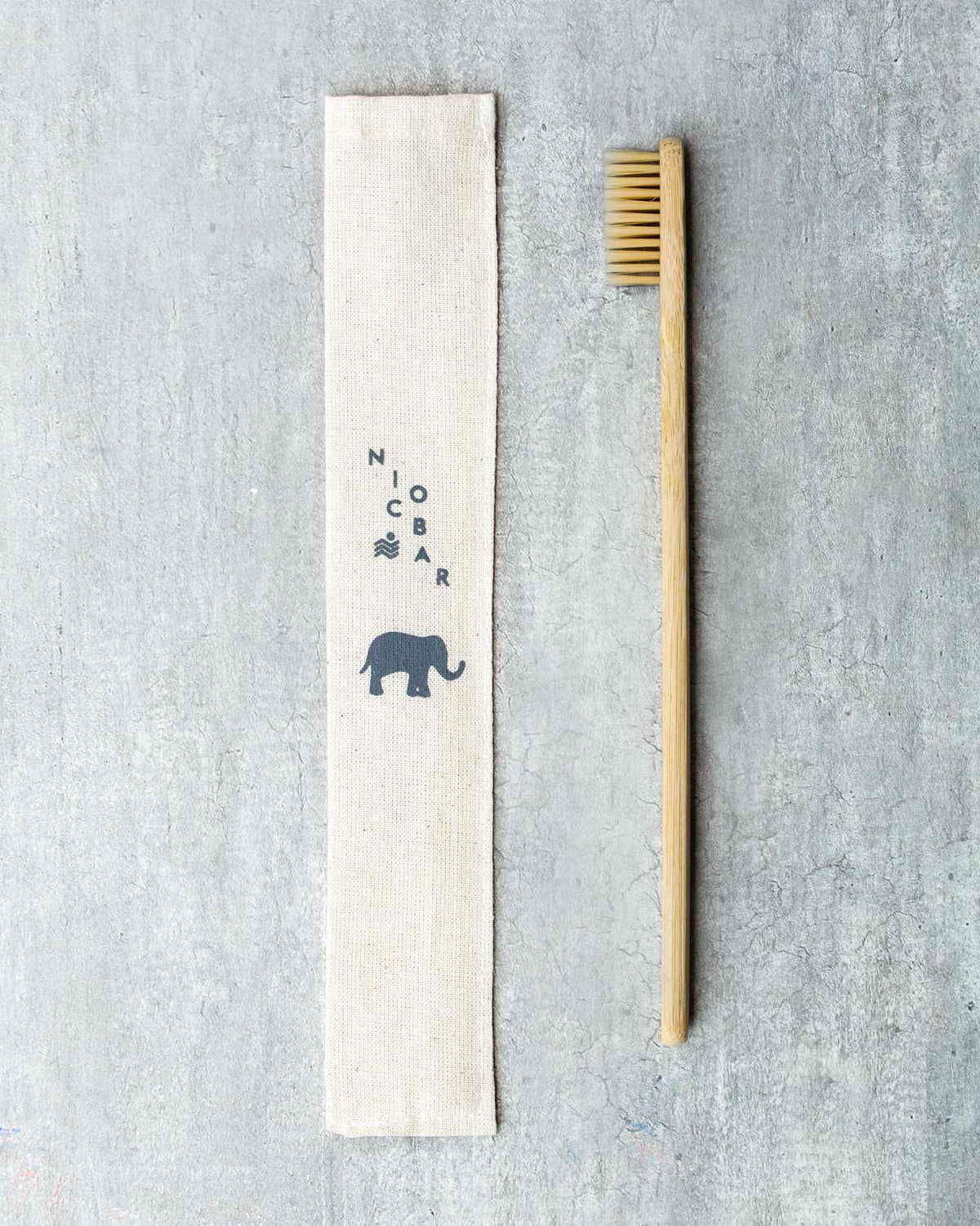 Bamboo Toothbrush with natural bristles beside a cotton pouch printed with an elephant.